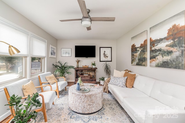 living area featuring ceiling fan, baseboards, and wood finished floors