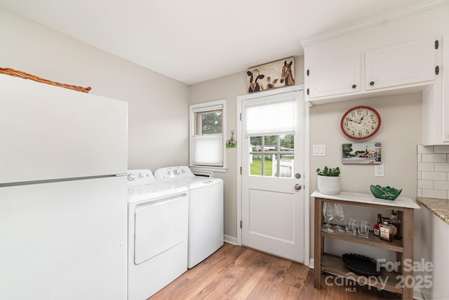 washroom with light wood-type flooring, washing machine and dryer, and cabinet space