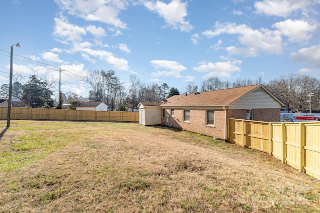 view of yard featuring a fenced backyard, an outdoor structure, and a storage unit