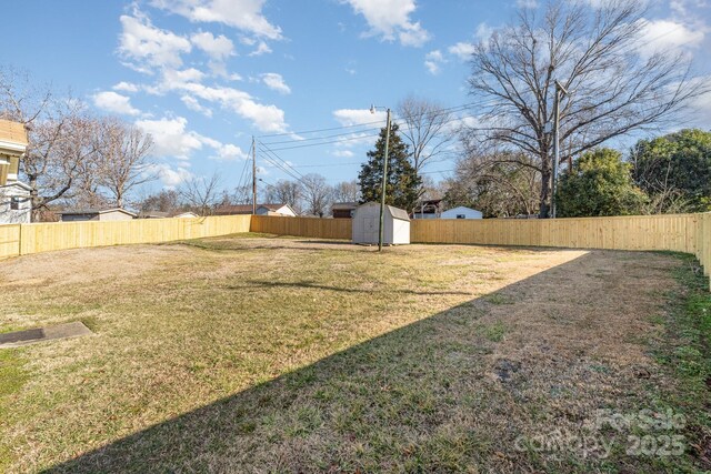 view of yard with an outbuilding, a fenced backyard, and a storage shed