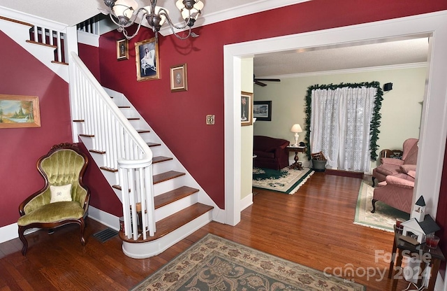 stairs featuring crown molding, a chandelier, hardwood / wood-style flooring, and a textured ceiling