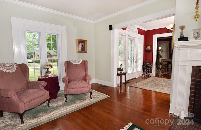 sitting room with a fireplace, crown molding, wood-type flooring, and a notable chandelier