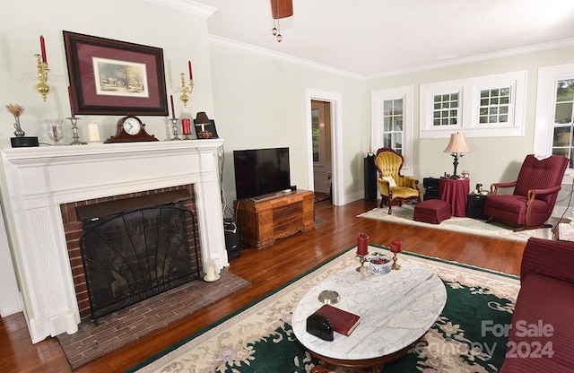 living room featuring dark hardwood / wood-style flooring, a brick fireplace, and ornamental molding