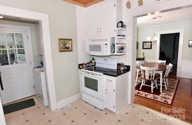 kitchen featuring washer and clothes dryer, white appliances, a chandelier, white cabinets, and light hardwood / wood-style floors