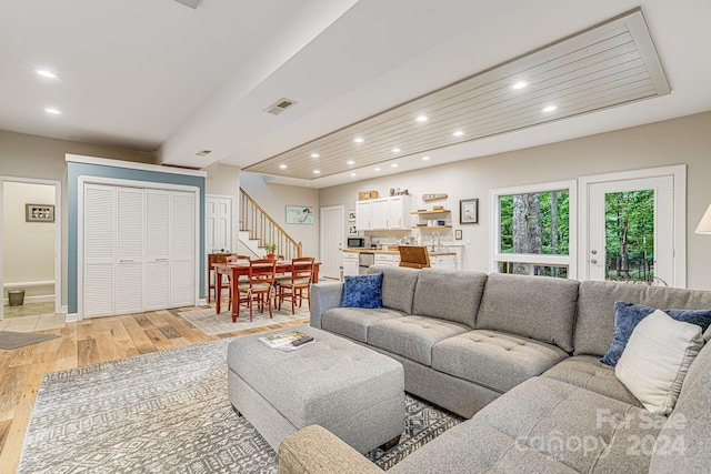 living area featuring recessed lighting, light wood-type flooring, visible vents, and stairs