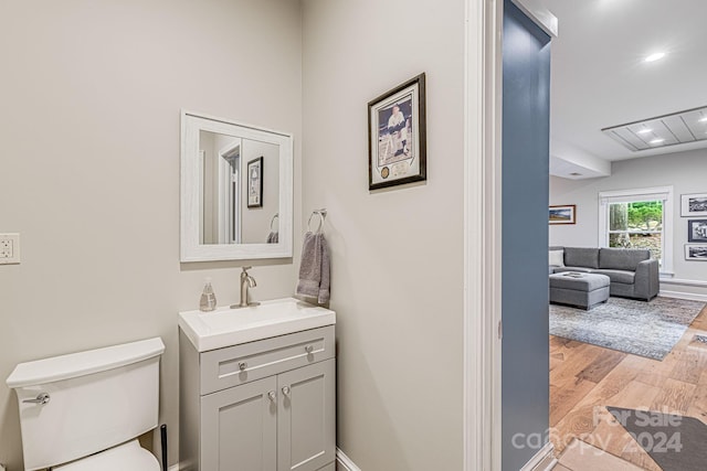 bathroom with baseboards, toilet, wood finished floors, and vanity