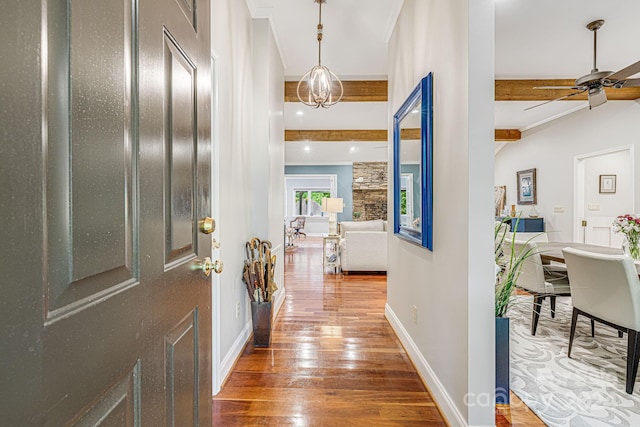 foyer with beam ceiling, ornamental molding, wood finished floors, baseboards, and ceiling fan