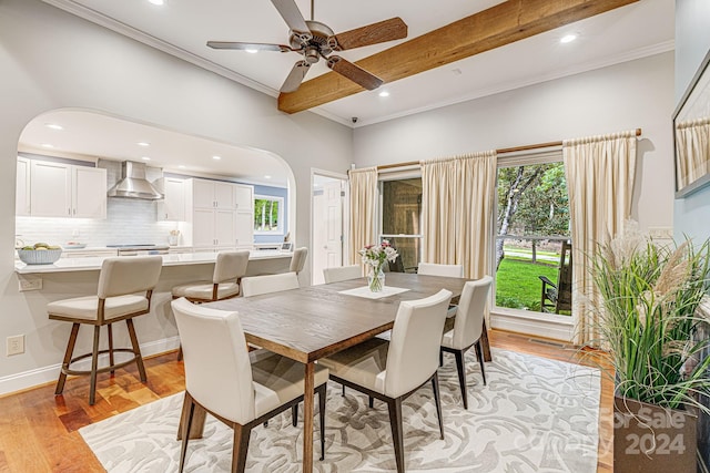 dining area featuring beam ceiling, light wood-style flooring, recessed lighting, arched walkways, and crown molding