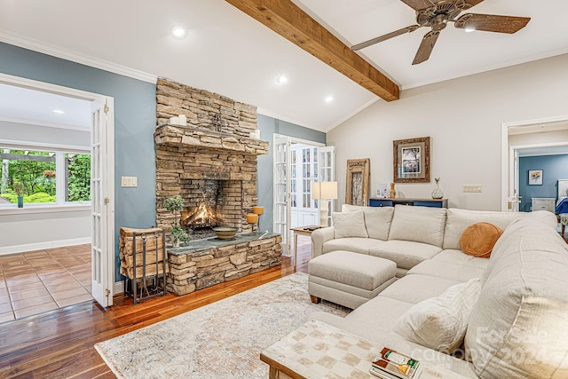 living area with baseboards, lofted ceiling with beams, ornamental molding, a stone fireplace, and wood finished floors