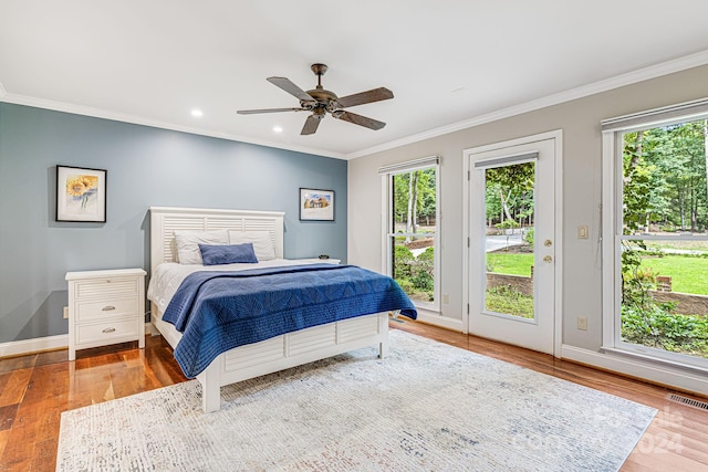 bedroom with wood finished floors, visible vents, baseboards, crown molding, and access to outside