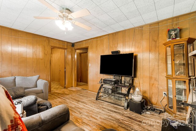 living room featuring hardwood / wood-style flooring, ceiling fan, and wood walls