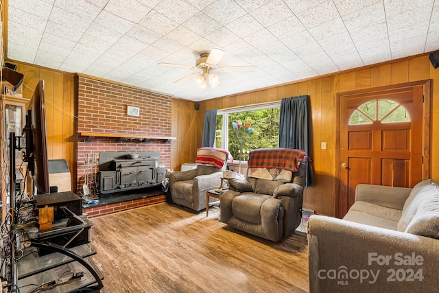 living room featuring ceiling fan, wood walls, light hardwood / wood-style flooring, and crown molding