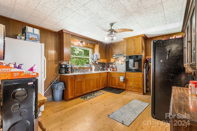 kitchen featuring light hardwood / wood-style flooring, tasteful backsplash, exhaust hood, black appliances, and sink