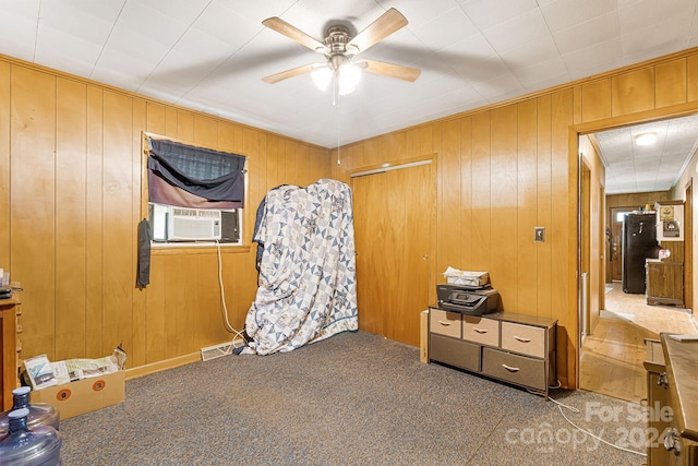 interior space with cooling unit, carpet, ceiling fan, and wood walls