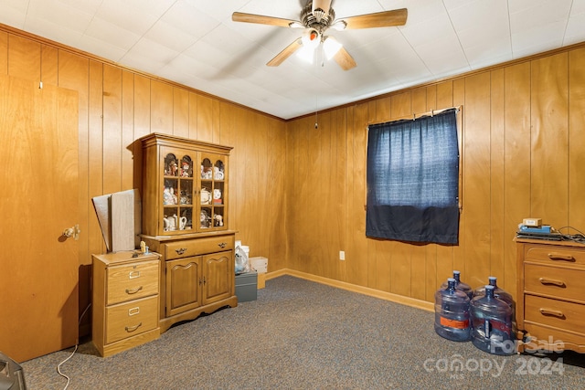 miscellaneous room with carpet floors, wooden walls, and ceiling fan