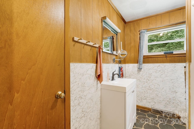 bathroom with vanity, crown molding, and wood walls