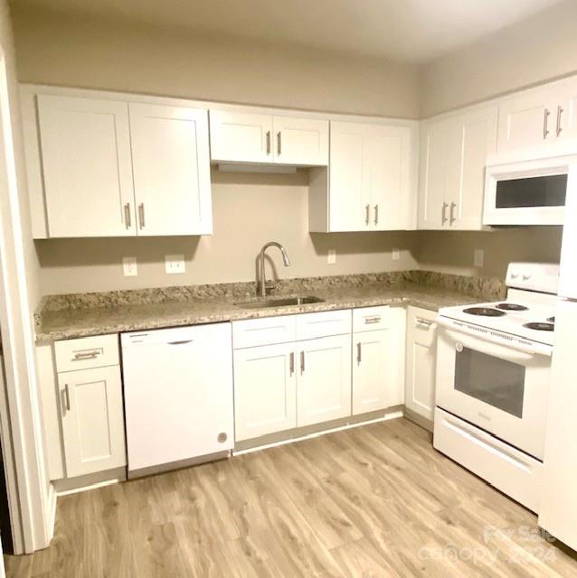 kitchen with light wood-type flooring, sink, white appliances, and white cabinetry