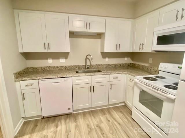 kitchen with light wood-type flooring, sink, white appliances, white cabinetry, and light stone countertops