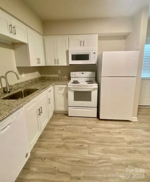 kitchen with light wood-type flooring, white appliances, sink, light stone counters, and white cabinets