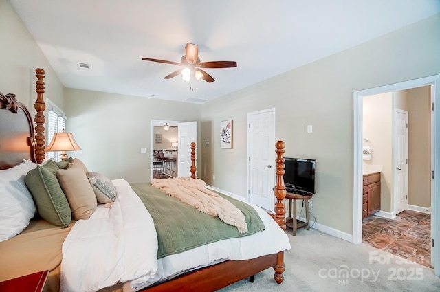 bedroom featuring light carpet, visible vents, baseboards, ceiling fan, and ensuite bathroom