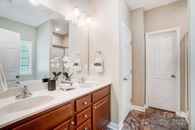 bathroom with double vanity, a garden tub, baseboards, and a sink