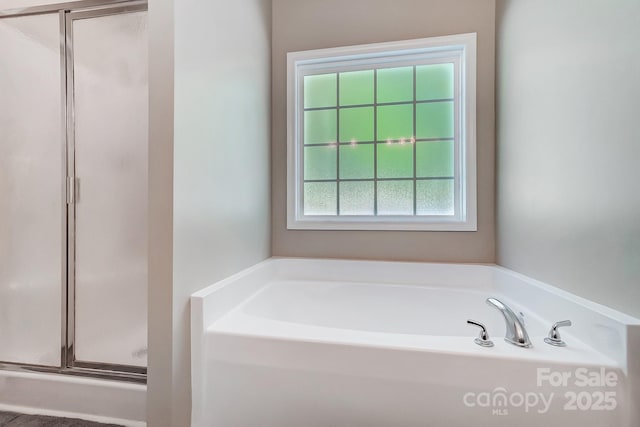 bathroom featuring a shower stall and a bath