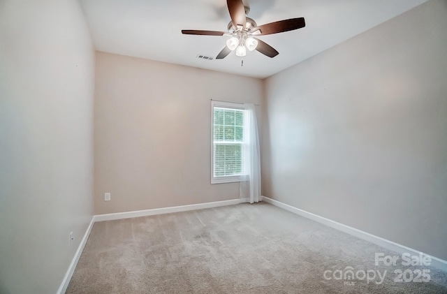 carpeted spare room with visible vents, ceiling fan, and baseboards