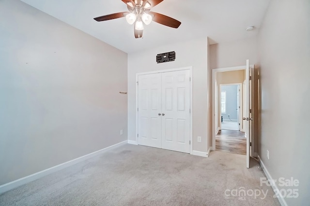 unfurnished bedroom featuring carpet floors, a closet, baseboards, and a ceiling fan