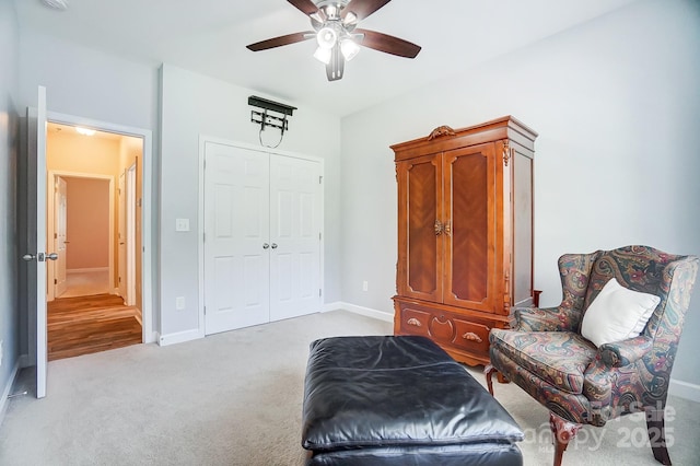 sitting room with light carpet, a ceiling fan, and baseboards