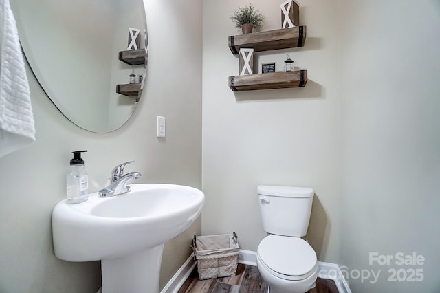 bathroom with baseboards, a sink, toilet, and wood finished floors