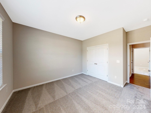 unfurnished bedroom with a closet and light colored carpet