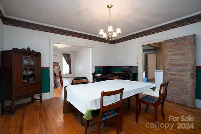 dining area with ornamental molding, wood-type flooring, and a chandelier