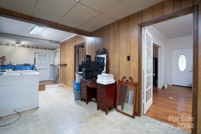 home office featuring wood walls, light wood-type flooring, and ornamental molding