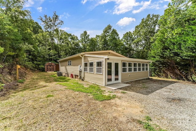 exterior space with central AC unit, french doors, and a shed