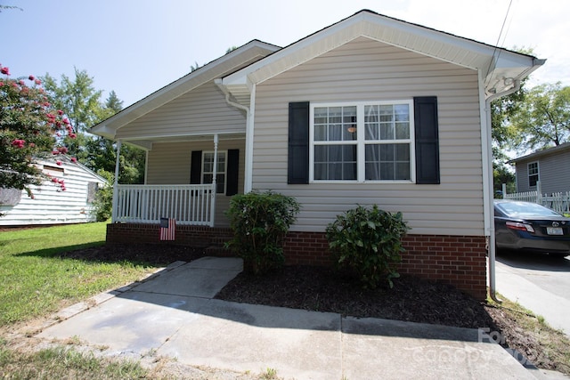 bungalow with covered porch and a front lawn