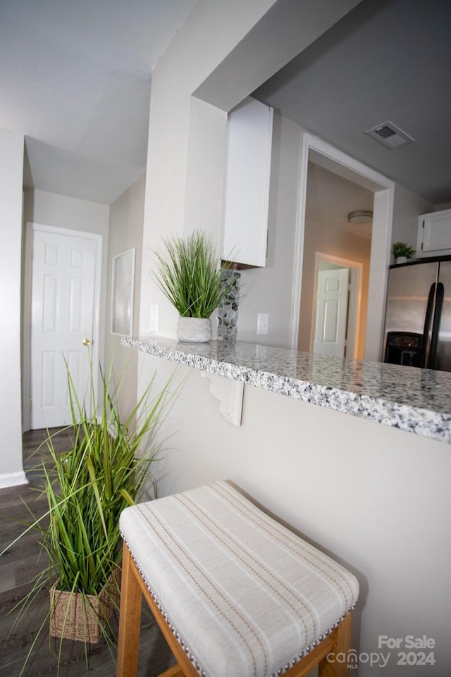 interior space with stainless steel fridge with ice dispenser and light stone counters