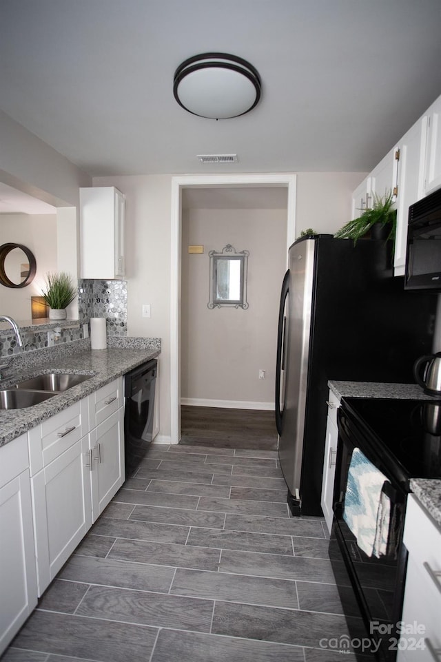 kitchen featuring sink, light stone counters, black appliances, and white cabinets