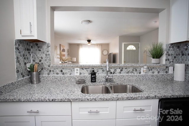 kitchen with sink, backsplash, light stone counters, white cabinetry, and dishwasher