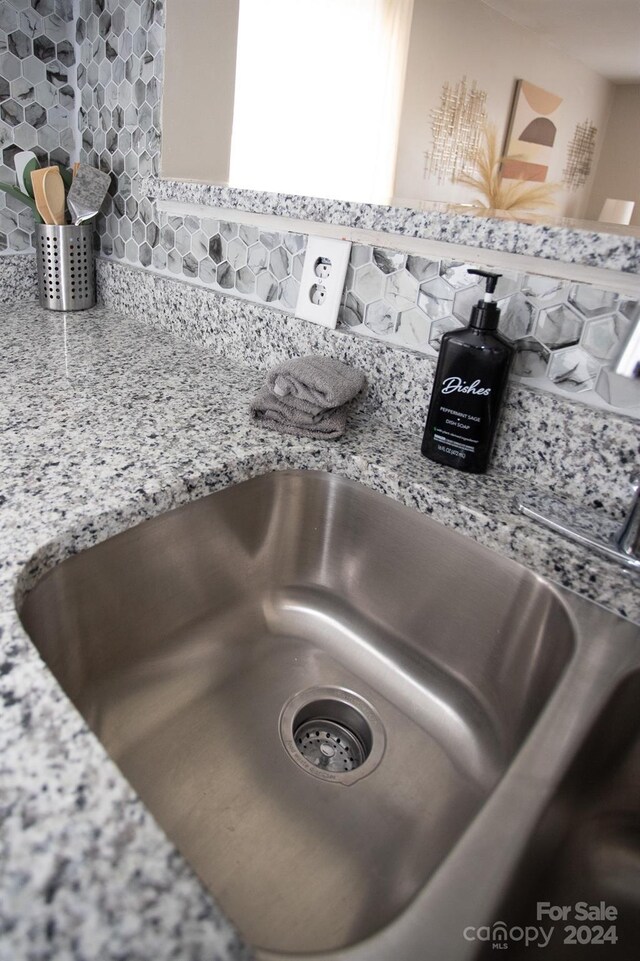 room details featuring sink, tasteful backsplash, and light stone counters