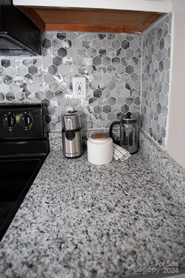 details with light stone countertops, tasteful backsplash, and black range oven