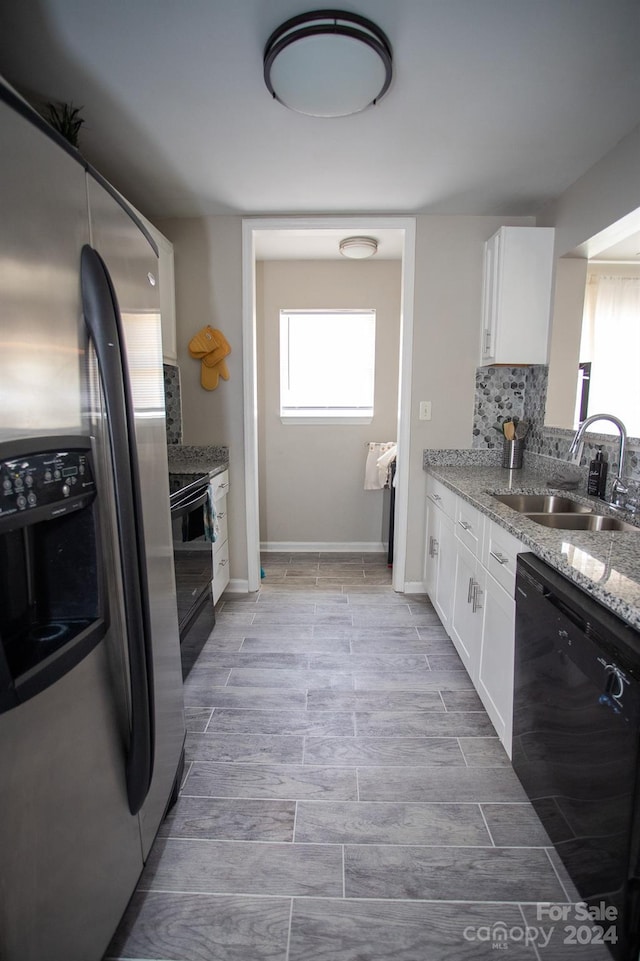 kitchen with sink, black appliances, a wealth of natural light, and white cabinets