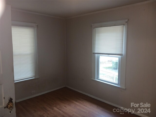 empty room with hardwood / wood-style flooring and crown molding