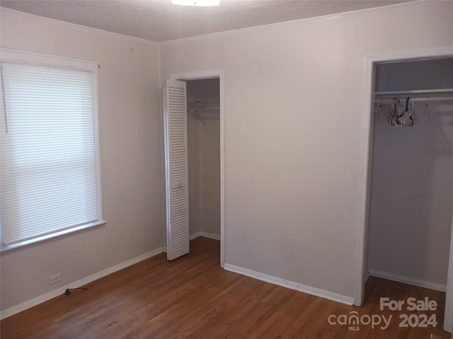 unfurnished bedroom with ornamental molding, wood-type flooring, and a textured ceiling