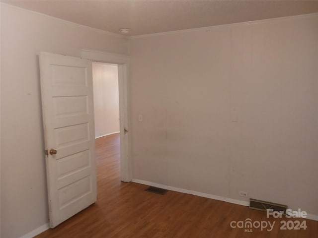 empty room with wood-type flooring and ornamental molding