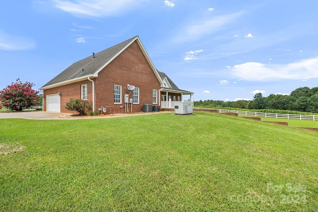 view of side of property featuring concrete driveway, fence, a yard, central air condition unit, and brick siding