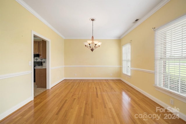 empty room with ornamental molding, light wood-style flooring, visible vents, and a notable chandelier