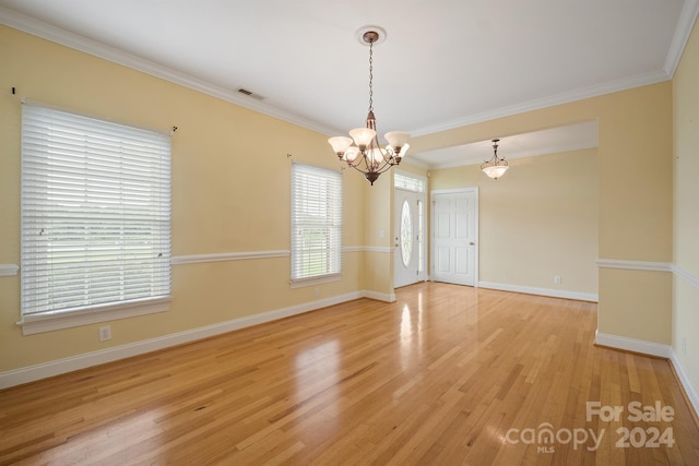 spare room featuring crown molding, visible vents, a chandelier, light wood-type flooring, and baseboards