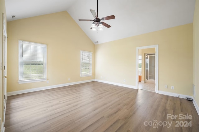 empty room with baseboards, visible vents, high vaulted ceiling, and wood finished floors