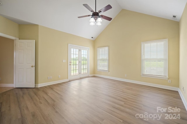 empty room featuring high vaulted ceiling, wood finished floors, visible vents, and baseboards