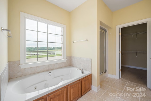 bathroom with a stall shower, a spacious closet, a jetted tub, and tile patterned floors